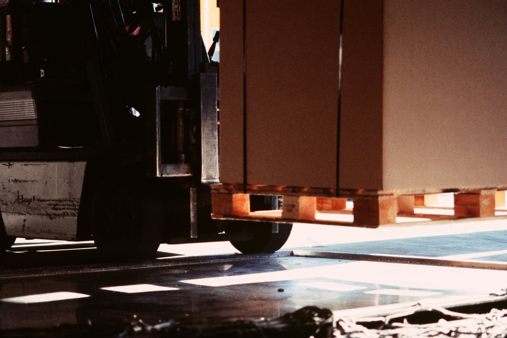 Fork-lift truck lifting large box in warehouse